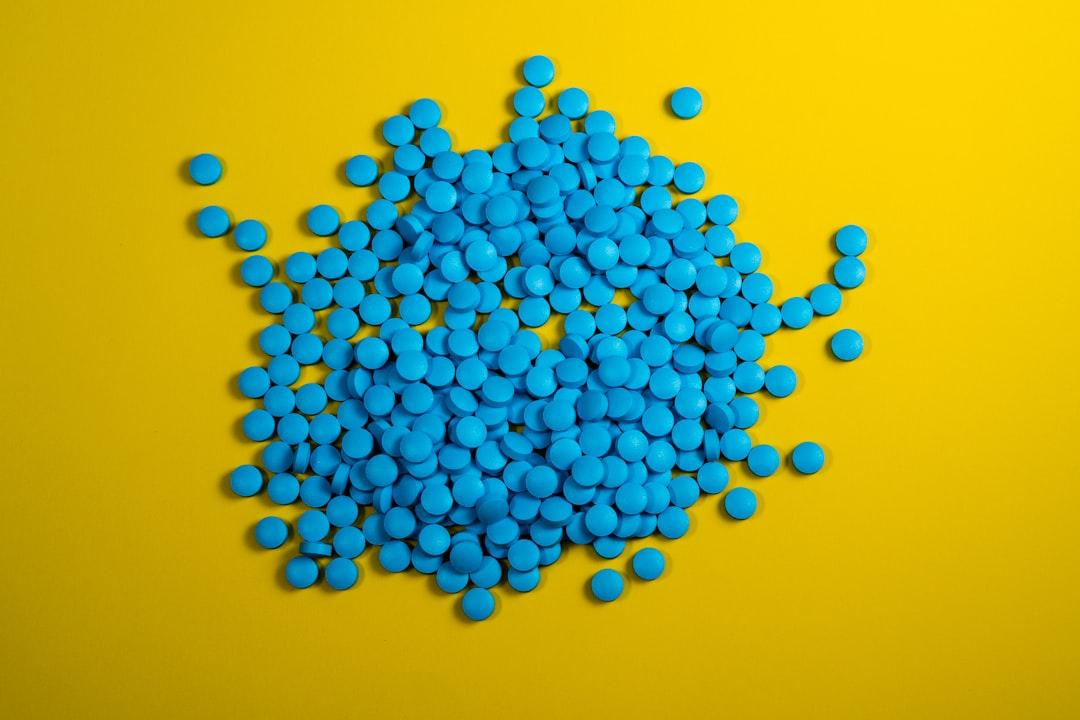 A pile of blue pills on a yellow background from Michał Parzuchowski on Unsplash SỰ RA ĐỜI CỦA VIÊN THUỐC TRỊ BÊNH BẤT LỰC VIAGRA