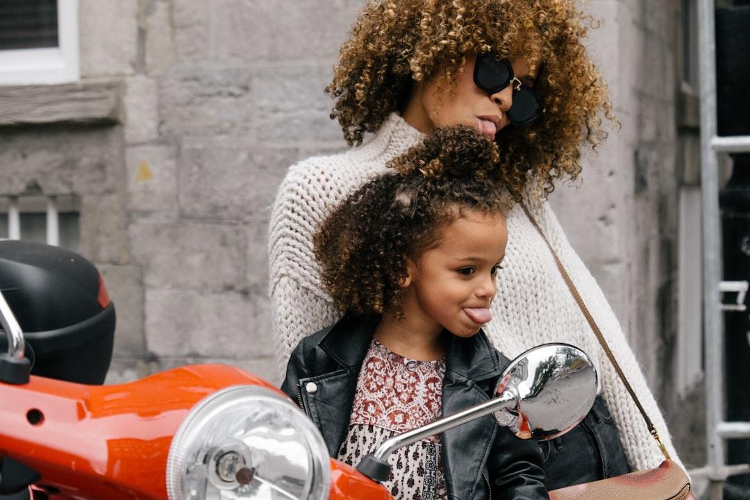 Woman and girl showing their tongues beside motorcycle from Sai De Silva on Unsplash