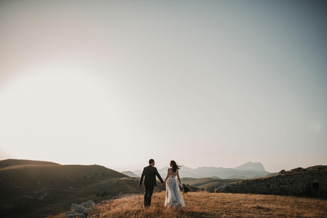 A bride and groom walking on a hill from Foto Pettine on Unsplash