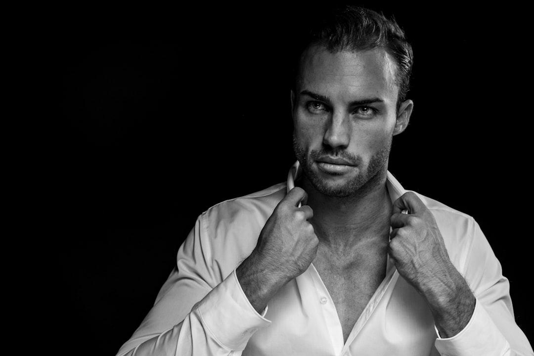 Grayscale portrait of man wearing white dress shirt on black background from Jens Lindner on Unsplash