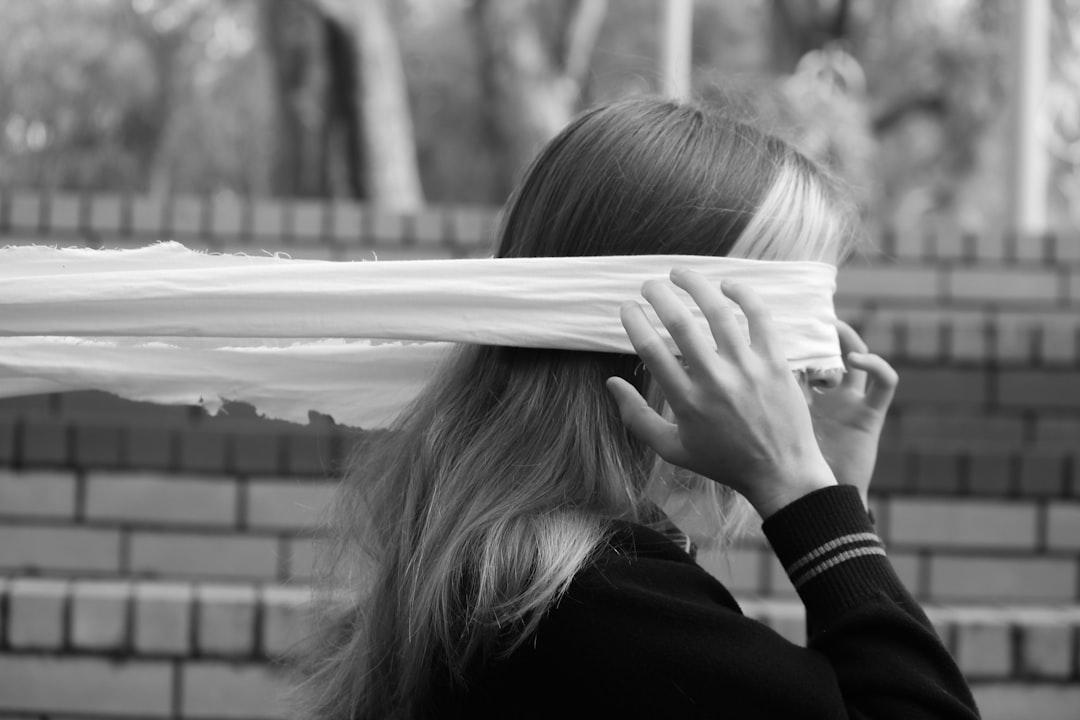 A woman covering her eyes with a white sheet from Amber Weir on Unsplash