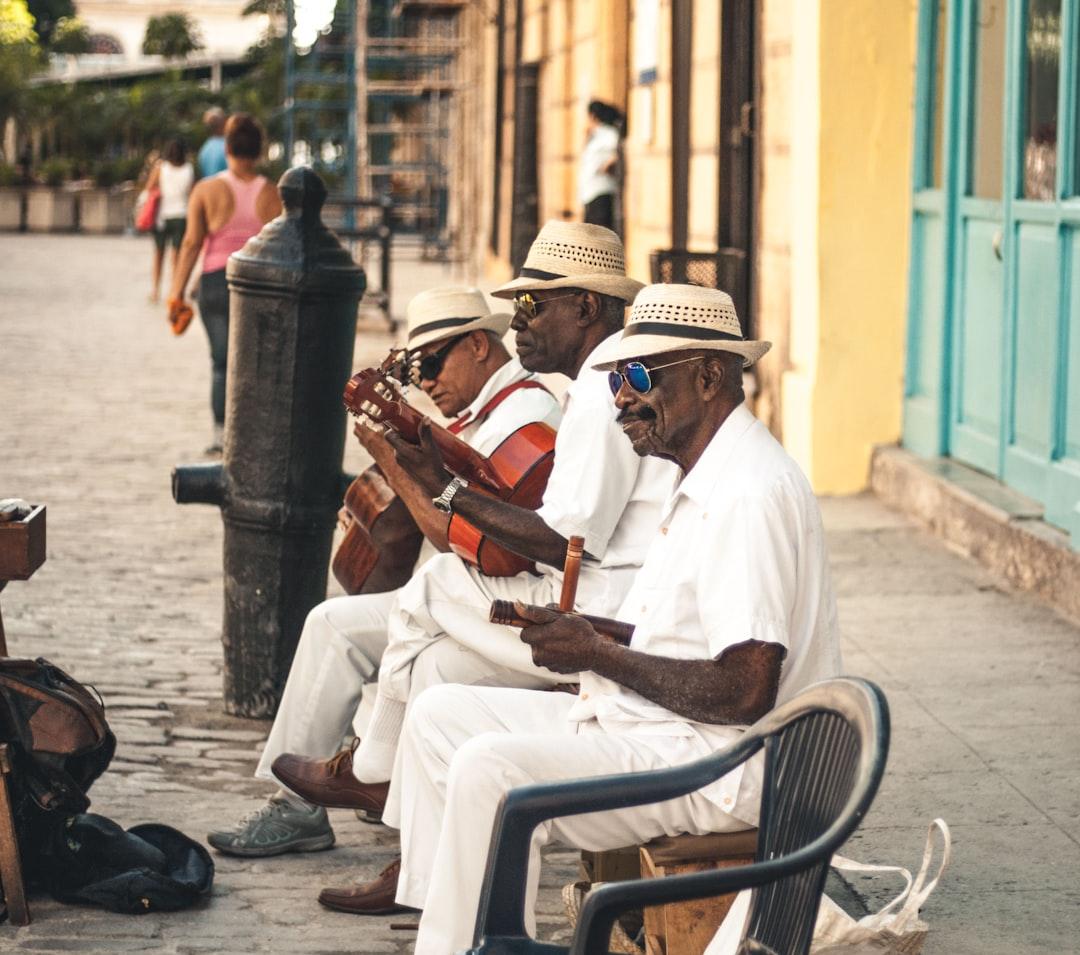 Man playing acoustic guitar while sitting on bench from Ban Yido on Unsplash