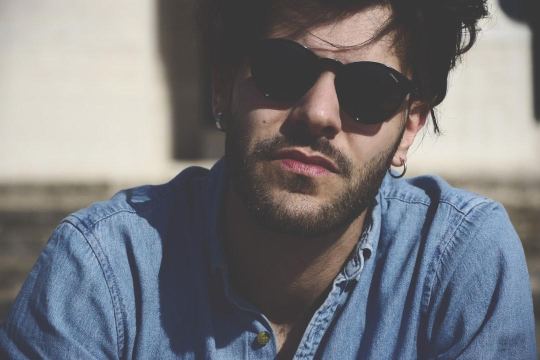 Man wearing blue denim top and black sunglasses from Andrea Dibitonto on Unsplash