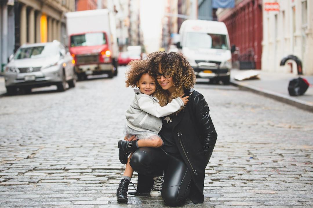 Photography of woman carrying baby near street during daytime from Sai De Silva on Unsplash