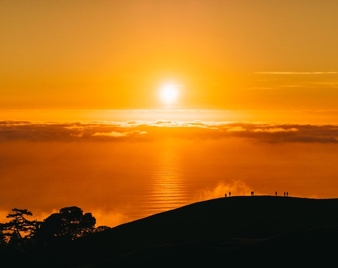 People on top of hill under white clouds golden hour photography from JOHN TOWNER on Unsplash