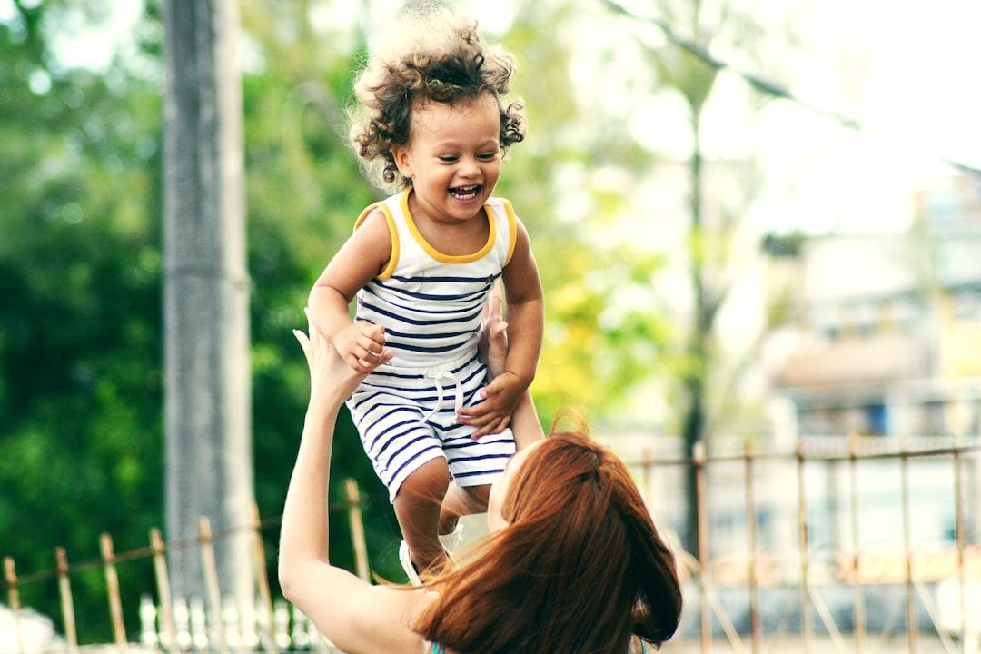 Selective focus photo of woman lifting child during daytime from Thiago Cerqueira on Unsplash