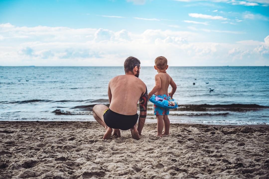 Man in black shorts holding blue plastic bucket on beach during daytime from Jan Kopřiva on Unsplash