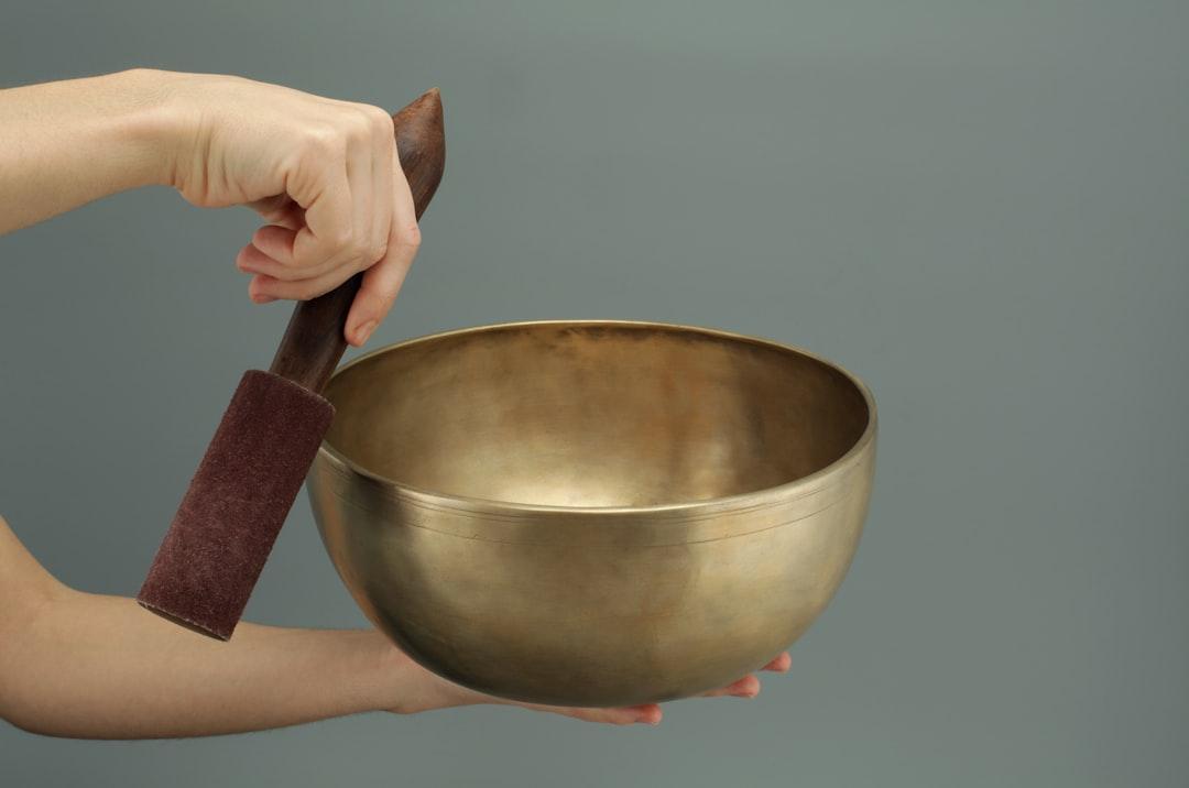 Person holding brass-colored song bowl set from Magic Bowls on Unsplash