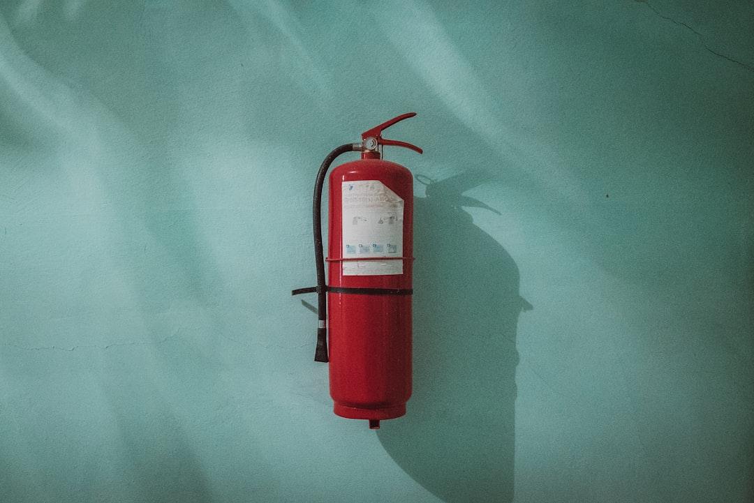 Red fire extinguisher on green wall from Piotr Chrobot on Unsplash