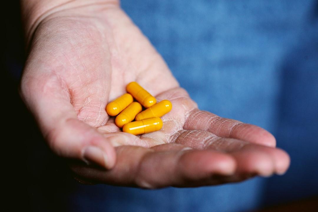 Yellow medication pill on persons hand from Alexander Grey on Unsplash