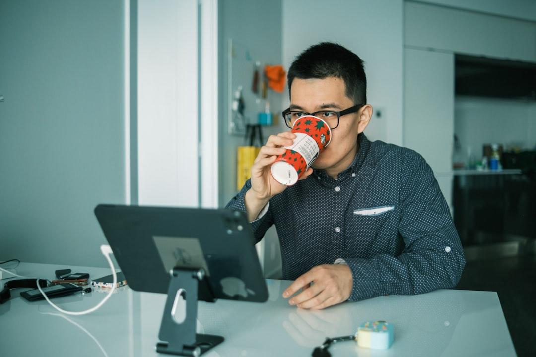 Man in black and white checkered dress shirt drinking from brown and white ceramic mug from Steve Ding on Unsplash