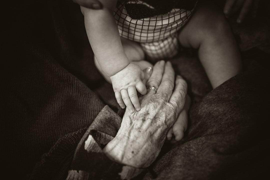 An older woman holding a baby's hand from Rod Long on Unsplash Phòng bệnh ung thư vú