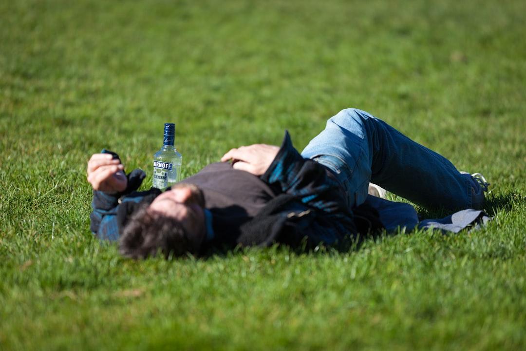 A man laying in the grass with a bottle of beer from thom masat on Unsplash Rượu làm rối loạn nhịp tim ở phụ nữ