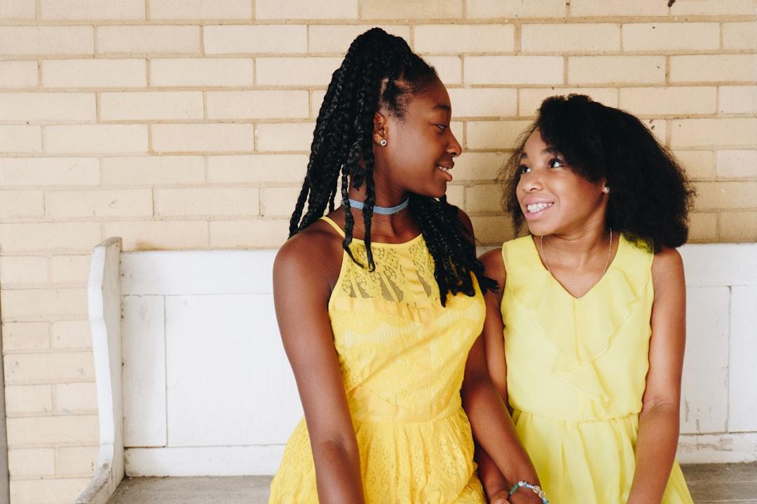Two girl's in yellow sleeveless dresses sitting on white wooden bench during daytime from Eye for Ebony on Unsplash 32,6% trẻ em suy dinh dưỡng thể thấp còi