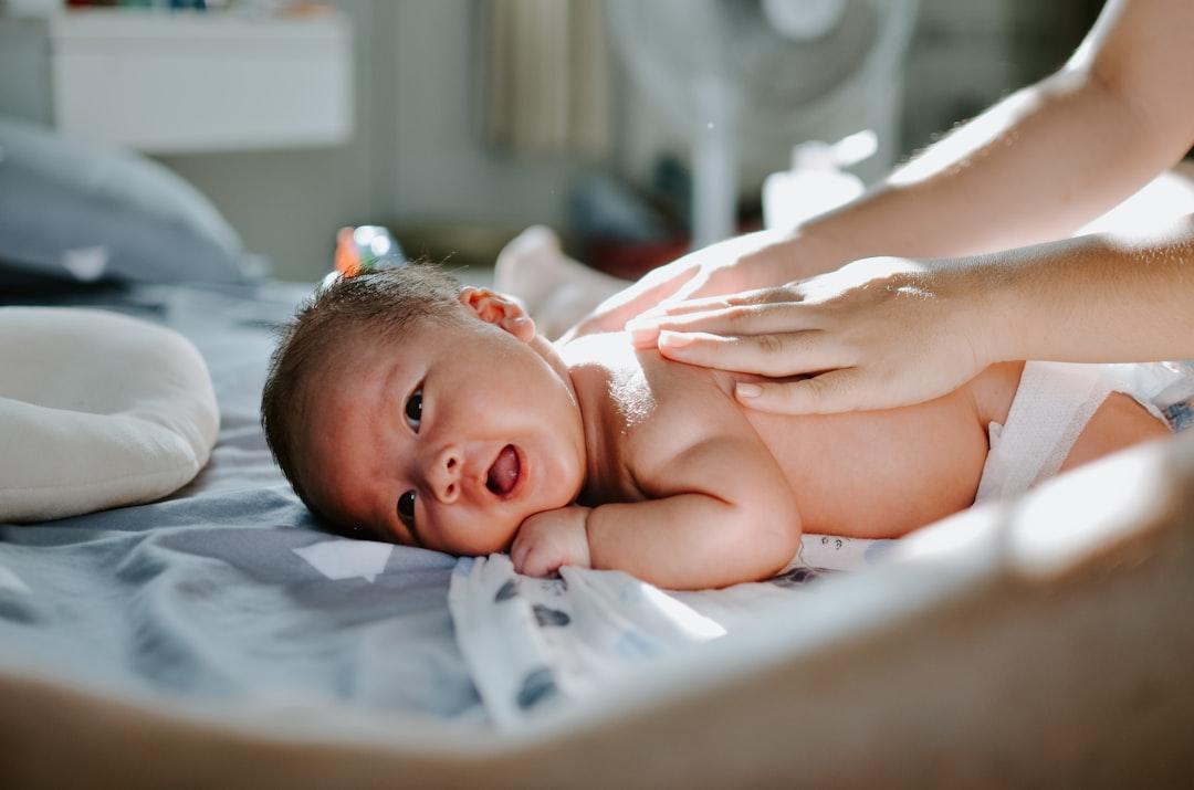 Baby laying on bed while woman massaging his back from Khoa Pham on Unsplash Một số cách đơn giản trị nhức đầu