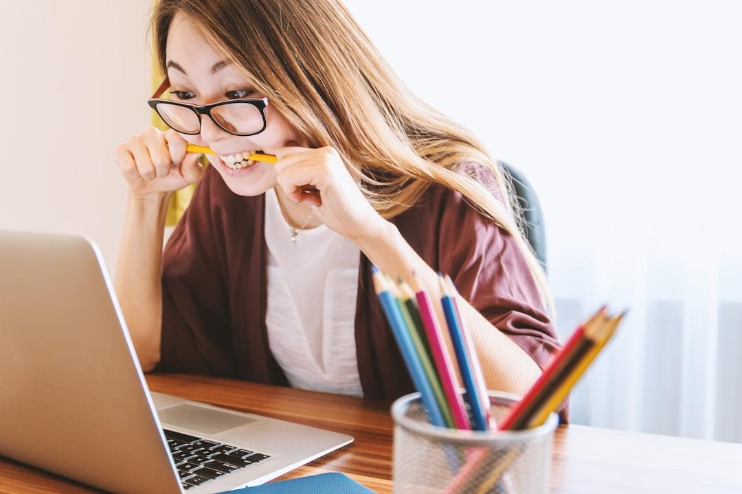 Woman biting pencil while sitting on chair in front of computer during daytime from JESHOOTS.COM on Unsplash Đau đầu do “xì-chét”