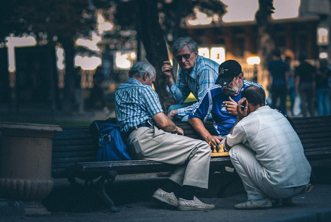 Man in blue and white plaid dress shirt sitting on bench from Egor Myznik on Unsplash Người Việt sống thọ trung bình 72 tuổi