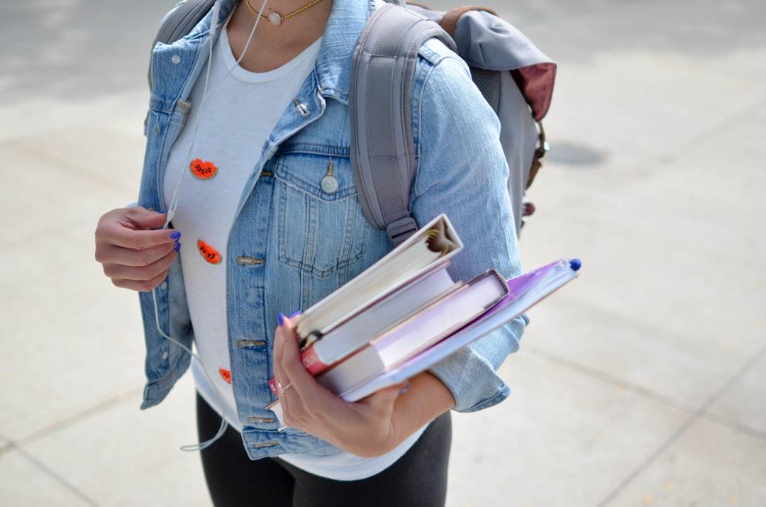 woman wearing blue denim jacket holding book Vấn đề tình dục trong ngành sư phạm