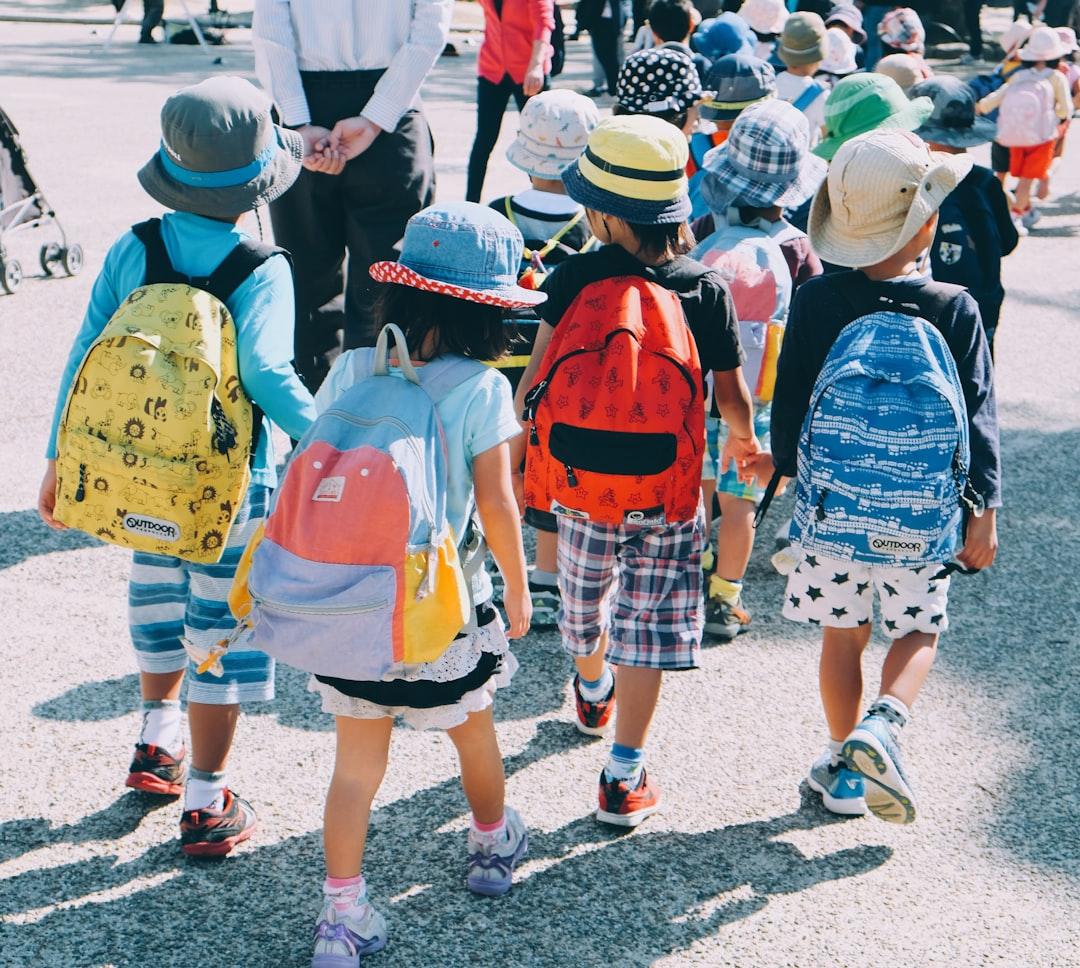 Group of people wearing white and orange backpacks walking on gray concrete pavement during daytime from note thanun on Unsplash Học sinh và điều dưỡng viên nhiễm cúm A/H1N1