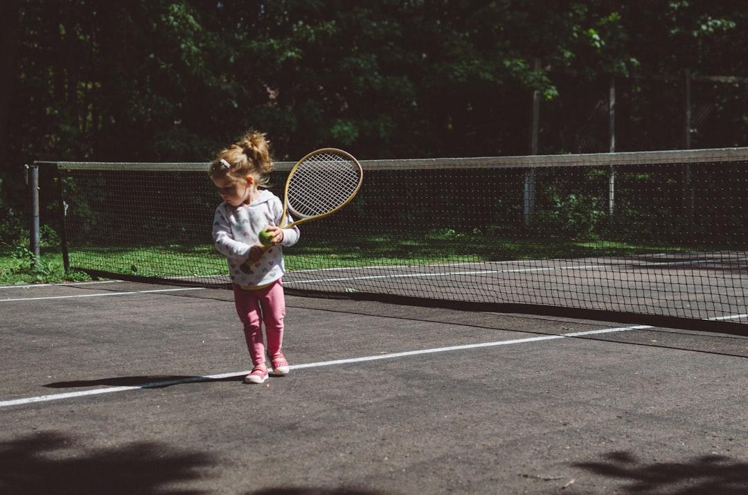 Girl holding lawn tennis racket while standing beside white and black net from Kelly Sikkema on Unsplash