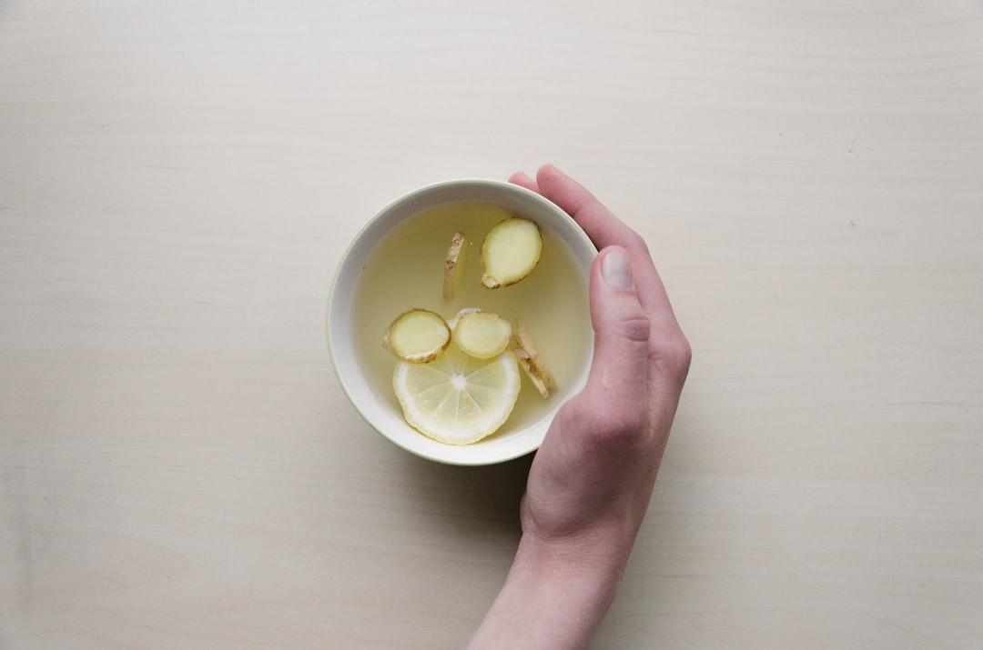 Person holding white bowl with sliced lime and ginger inside from Dominik Martin on Unsplash Hà Nội: Đình chỉ hai cơ sở sản xuất mứt bẩn