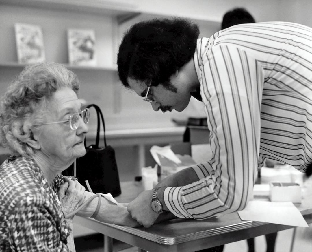 A man helping a woman with a piece of paper from CDC on Unsplash