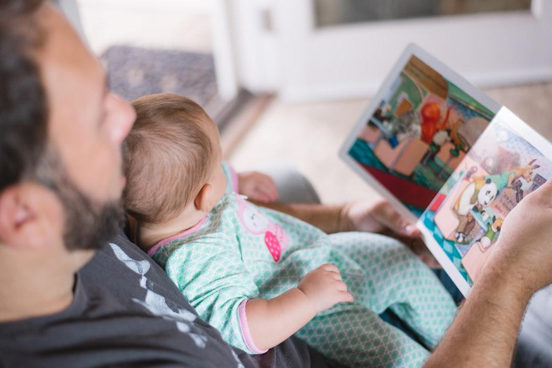 Person carrying baby while reading book from Picsea on Unsplash Chọn sữa cho con