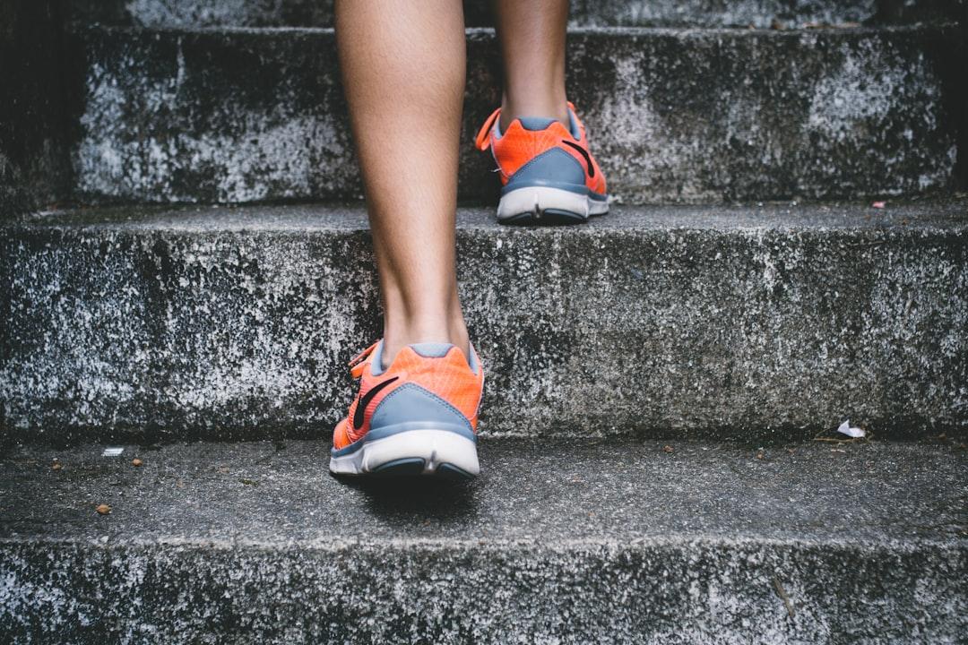 Person wearing orange and gray nike shoes walking on gray concrete stairs from Bruno Nascimento on Unsplash Chạy bộ - thần dược cho “chuyện ấy” của nam giới