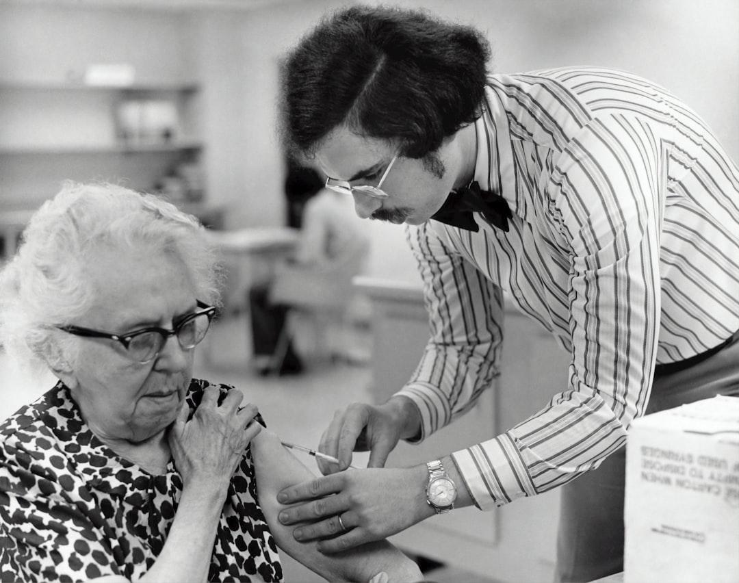 Grayscale photography of man holding syringe injecting on woman left arm from CDC on Unsplash