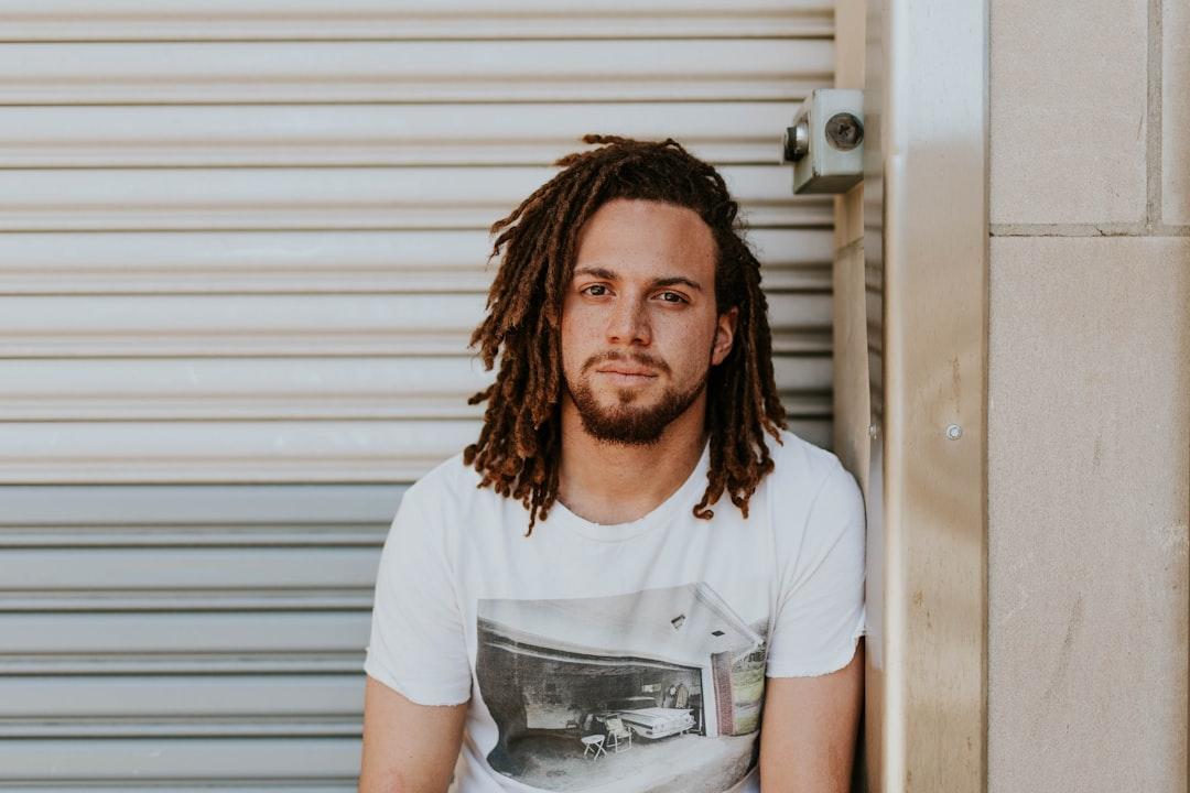 Man sitting near gray steel roller shutters during daytime from Brooke Cagle on Unsplash