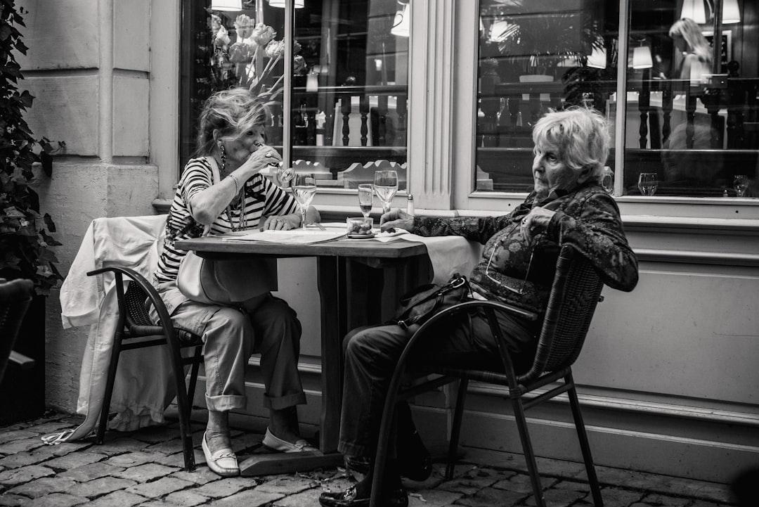 Grayscale photo of two woman sitting beside the table from Jez Timms on Unsplash