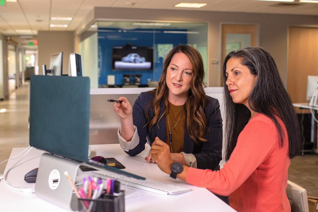 Two women sitting at a table looking at a computer screen from LinkedIn Sales Solutions on Unsplash