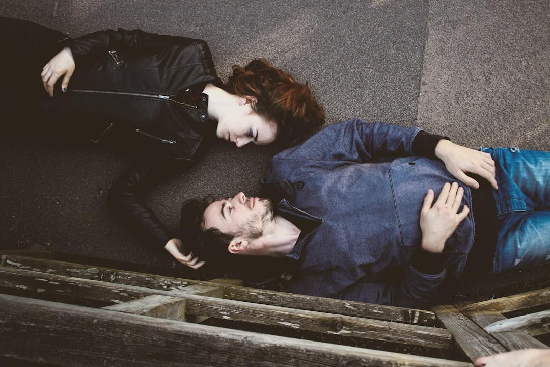 Man and woman lying on gray concrete surface looking at each other from Toa Heftiba on Unsplash