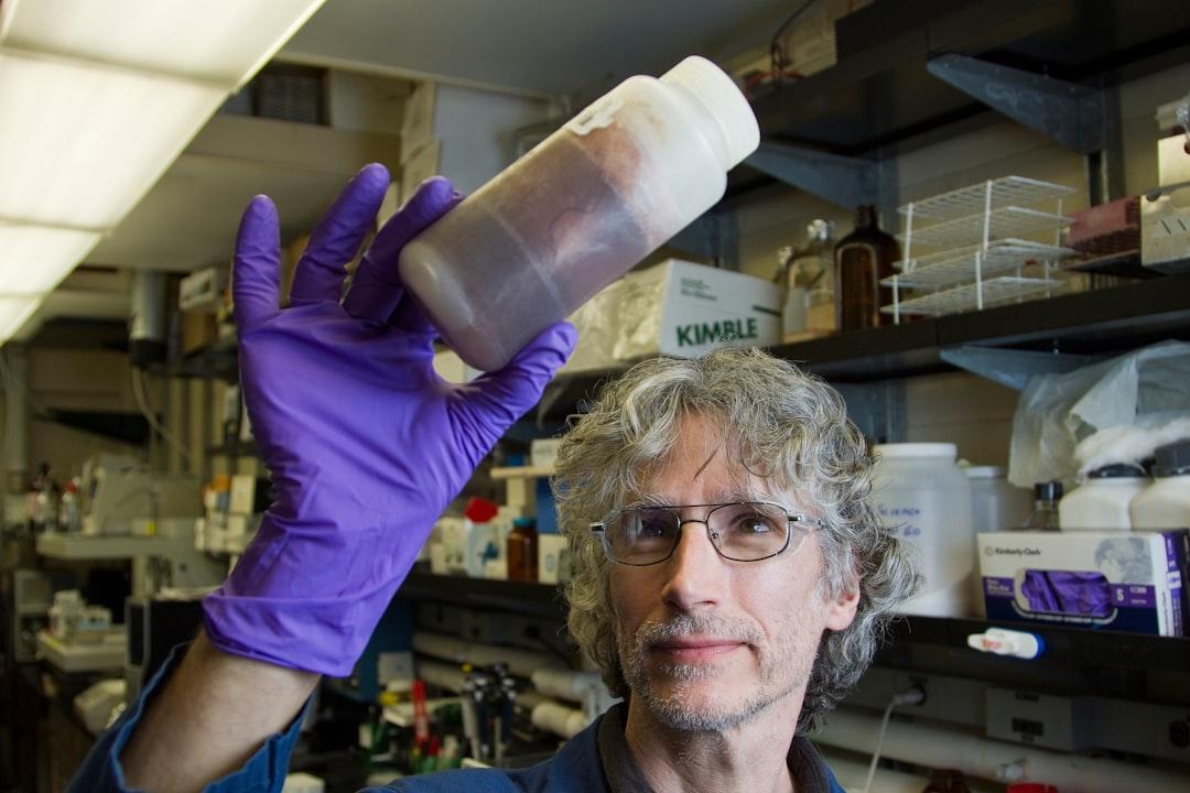Man in purple long sleeve shirt holding white plastic bottle from National Cancer Institute on Unsplash