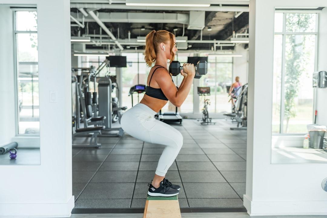 Woman wearing black sports bra and white legging lifting dummbells from Benjamin Klaver on Unsplash