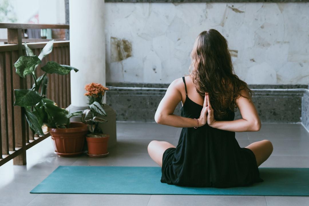 Woman wearing black shirt sitting on green yoga mat from Avrielle Suleiman on Unsplash