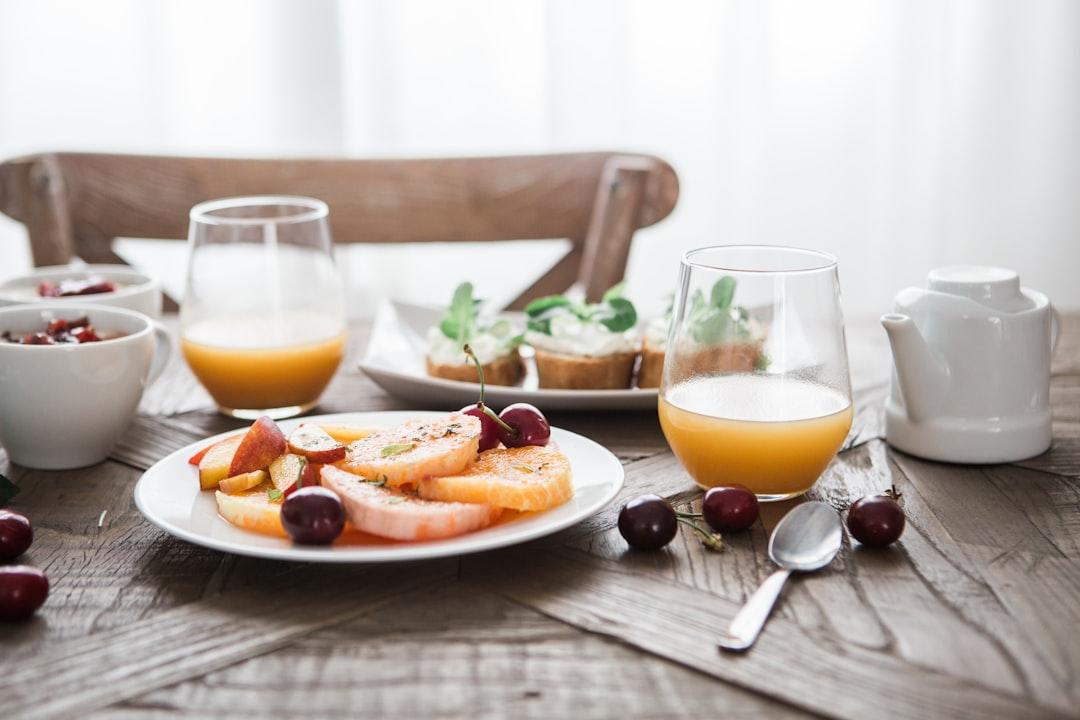 Slice fruits on plate on near glass cups from Brooke Lark on Unsplash