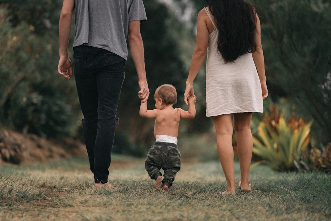 Couple walking barefoot with a child at the garden from Jakob Owens on Unsplash