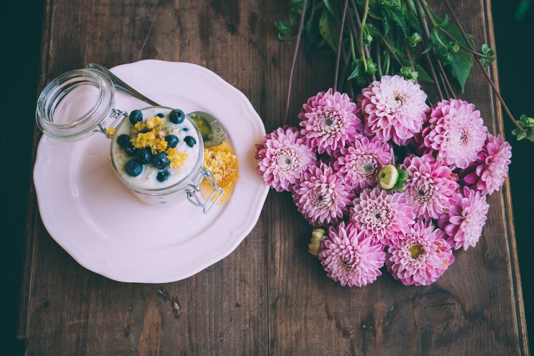 Pink dahlia flowers beside ceramic plate with jar from Alisa Anton on Unsplash