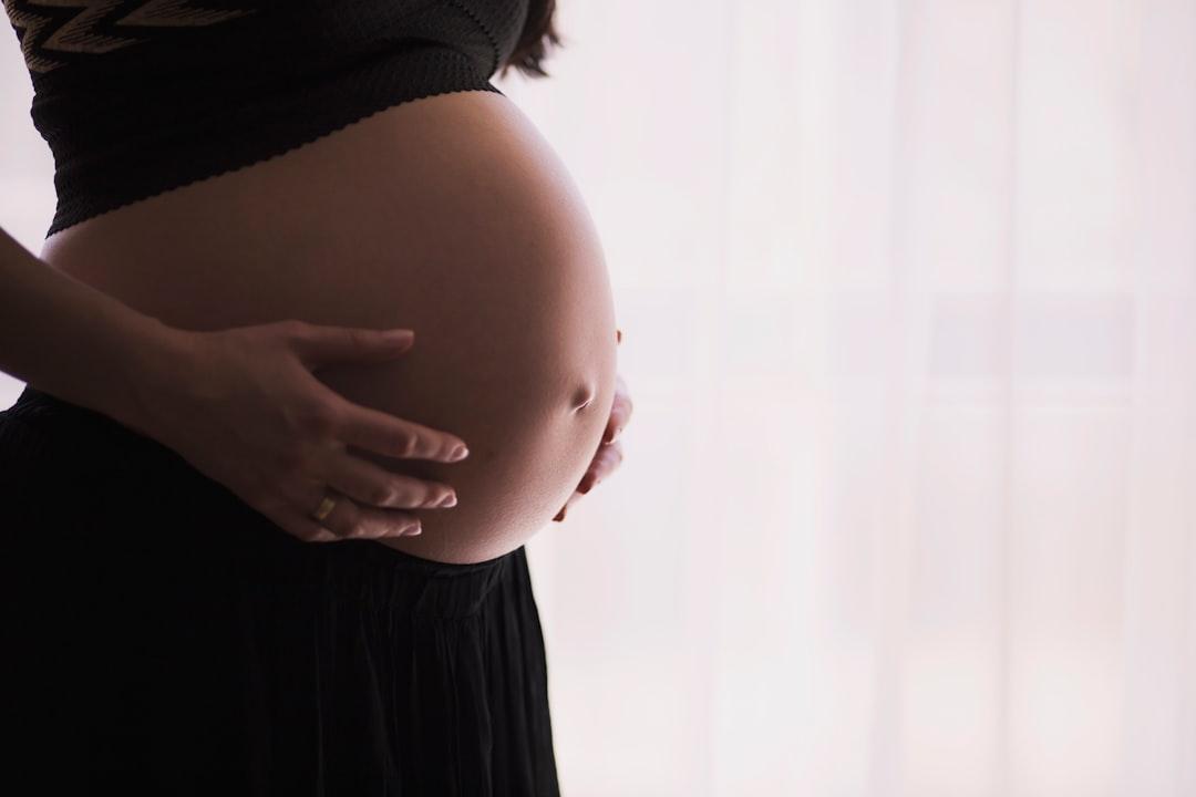 Woman holding stomach from freestocks on Unsplash Chuẩn bị sức khỏe và tinh thần trước khi mang thai