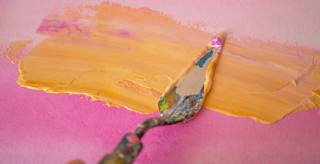 A person painting a pink wall with yellow paint from Kseniya Lapteva on Unsplash