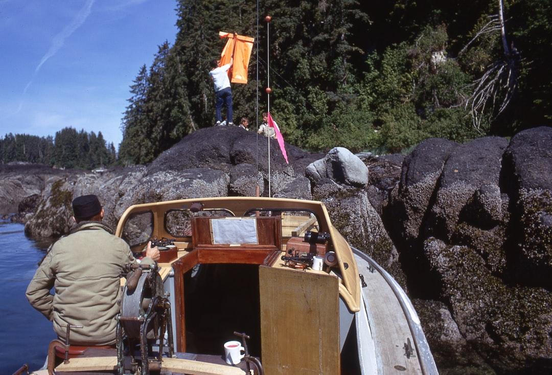man in brown jacket and brown pants standing beside brown wooden boat on rocky hill during Giới tính của một con người được quyết định vào khi nào và bởi những yếu