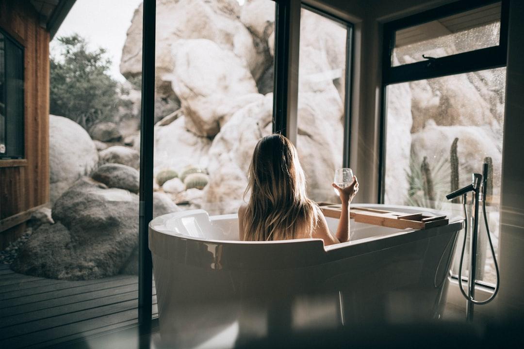 woman in white bathtub holding clear drinking glass Hội chứng tiền kinh nguyệt