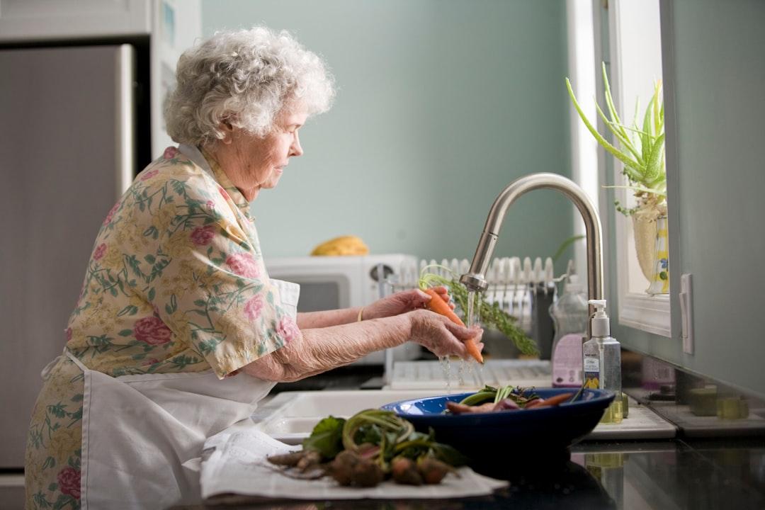 Woman wearing yellow and pink floral dress wahing carrots from CDC on Unsplash