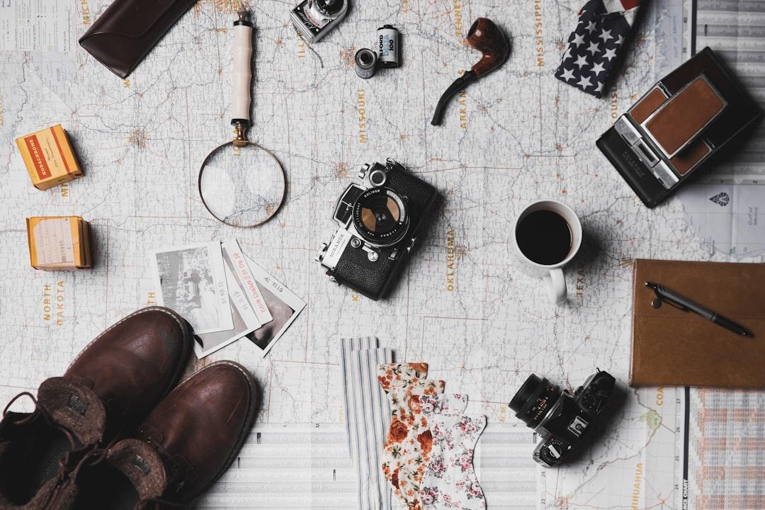 Camera, pair of brown shoes, white ceramic mug, grey and black pen, brown smoking pipe from ian dooley on Unsplash