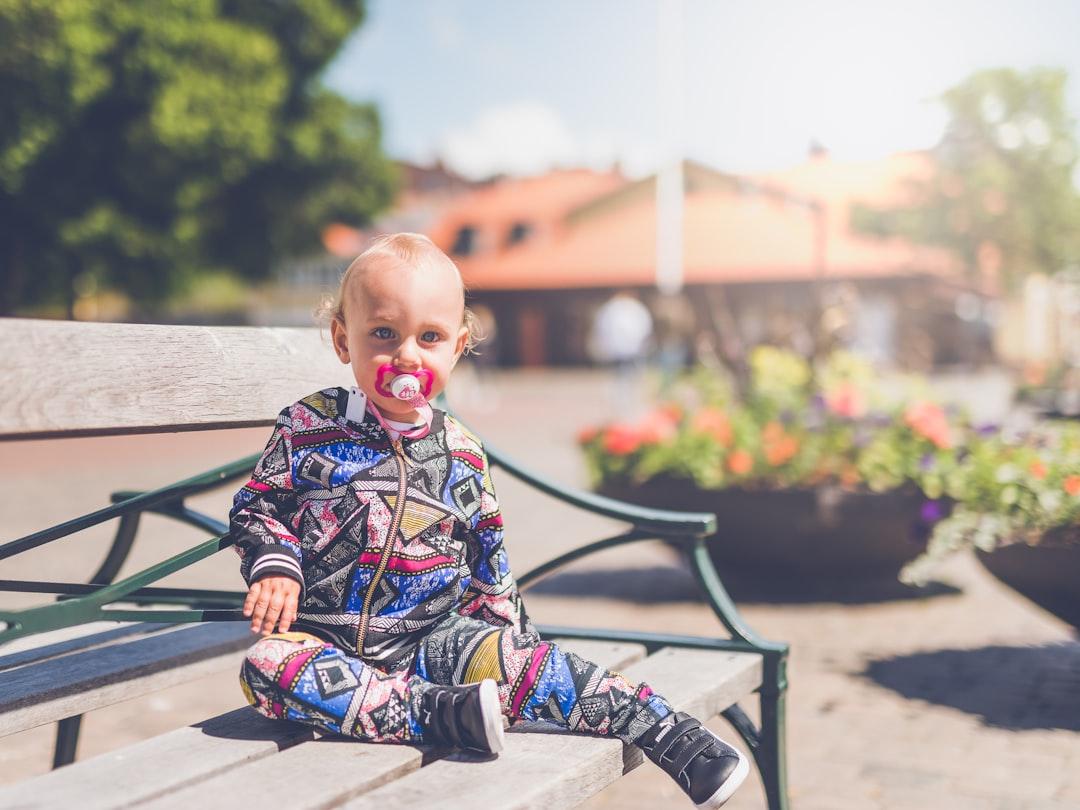 Toddler sitting on wooden bench from 🇸🇮 Janko Ferlič on Unsplash